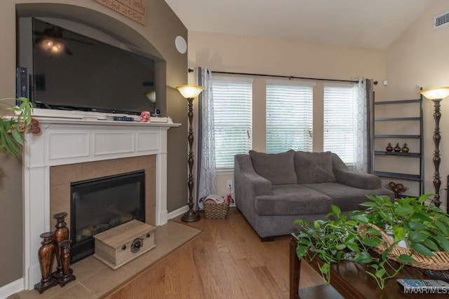 living room featuring lofted ceiling, a tile fireplace, and light hardwood / wood-style floors