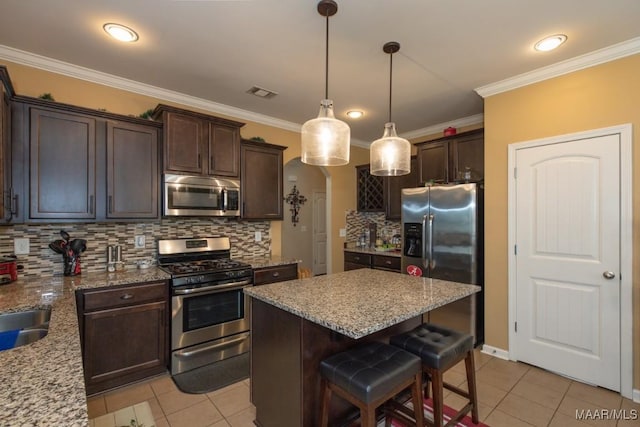 kitchen with pendant lighting, stainless steel appliances, a kitchen breakfast bar, light stone countertops, and light tile patterned flooring