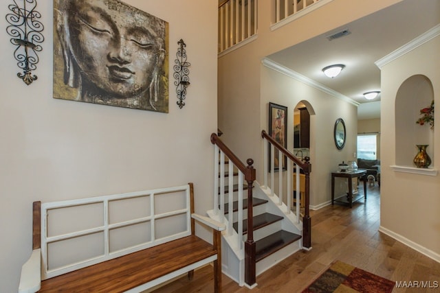 stairs with hardwood / wood-style flooring and crown molding