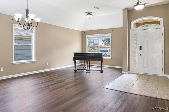 entryway with a notable chandelier, wood-type flooring, and lofted ceiling