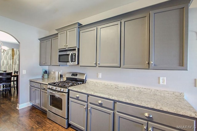 kitchen featuring gray cabinetry, dark hardwood / wood-style flooring, light stone countertops, and appliances with stainless steel finishes