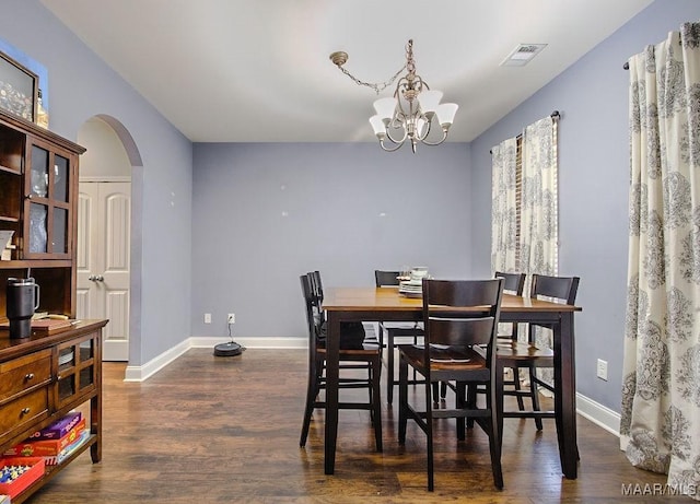 dining space with dark wood-type flooring and an inviting chandelier