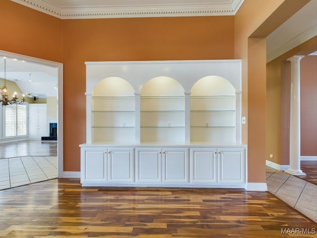 interior space with tile patterned flooring, decorative columns, a chandelier, built in shelves, and ornamental molding