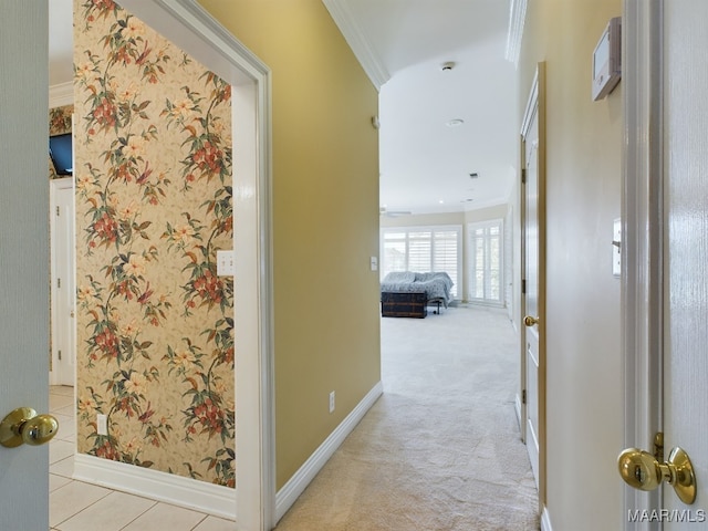 hall featuring baseboards, wallpapered walls, ornamental molding, and carpet