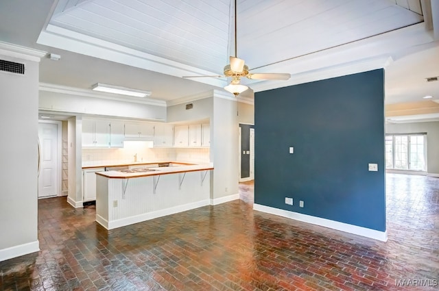 kitchen featuring white cabinetry, tasteful backsplash, ceiling fan, ornamental molding, and kitchen peninsula