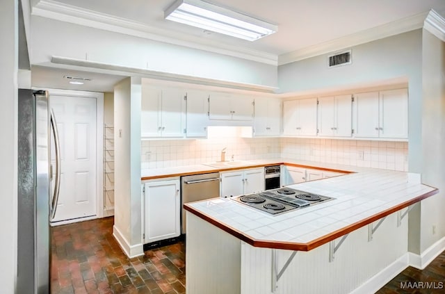 kitchen featuring backsplash, tile countertops, stainless steel appliances, and kitchen peninsula