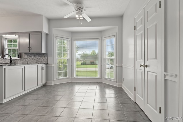 kitchen with tasteful backsplash, light tile patterned floors, ceiling fan, gray cabinets, and sink