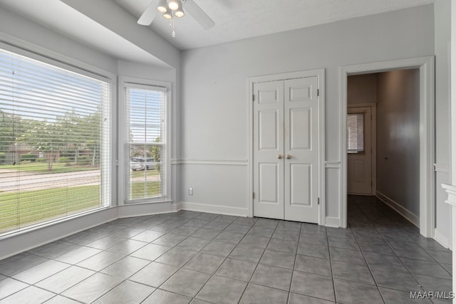 unfurnished bedroom with tile patterned flooring, multiple windows, a closet, and ceiling fan