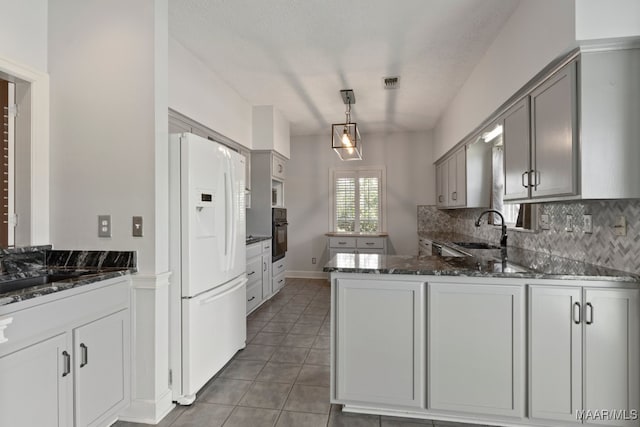 kitchen with sink, kitchen peninsula, tile patterned flooring, white refrigerator with ice dispenser, and black oven