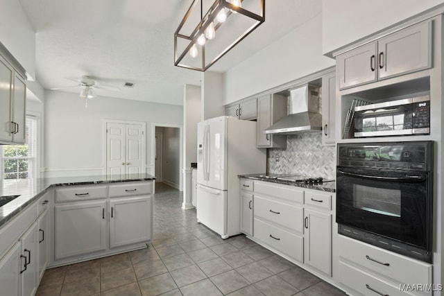 kitchen featuring gray cabinets, wall chimney range hood, ceiling fan, and black oven