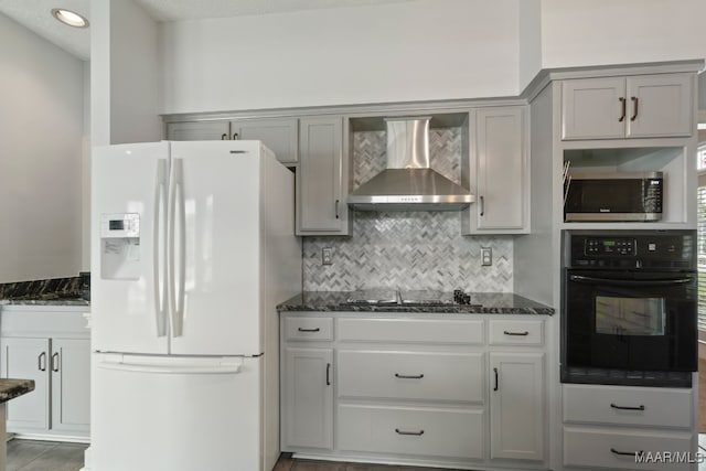 kitchen featuring dark stone countertops, white fridge with ice dispenser, gray cabinets, wall chimney exhaust hood, and oven