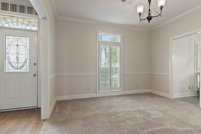 entryway featuring a chandelier, crown molding, light wood-type flooring, and a textured ceiling