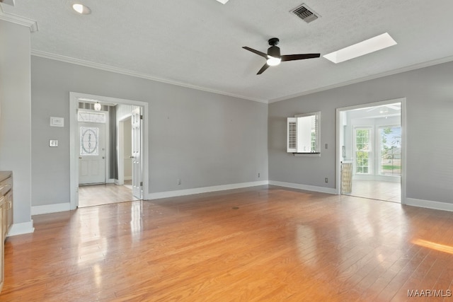 empty room with a skylight, light hardwood / wood-style flooring, ceiling fan, and crown molding