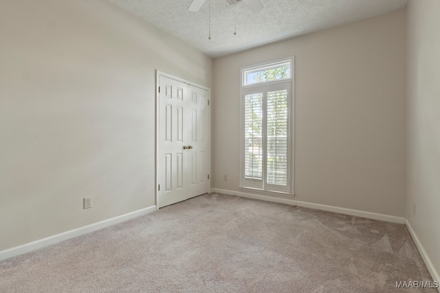 carpeted empty room with ceiling fan and a textured ceiling