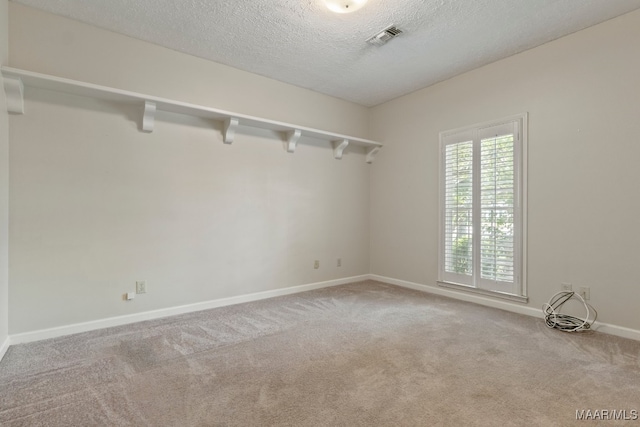 carpeted empty room featuring a textured ceiling