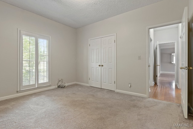 unfurnished bedroom with light carpet, a closet, and a textured ceiling