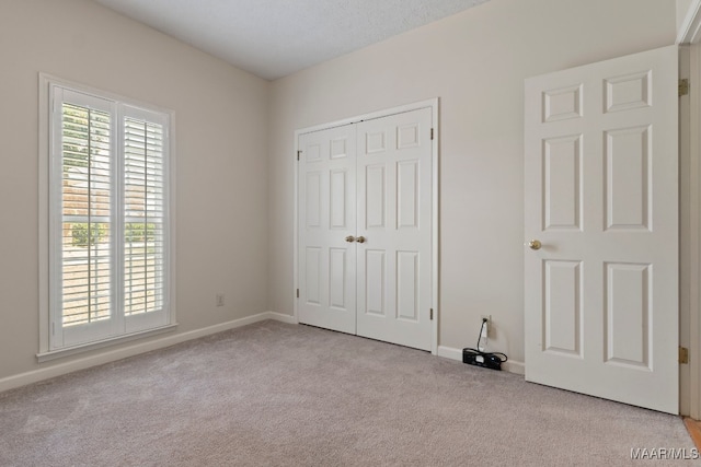 unfurnished bedroom featuring a closet and light colored carpet