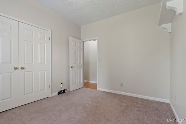 unfurnished bedroom with a closet, a textured ceiling, and light colored carpet