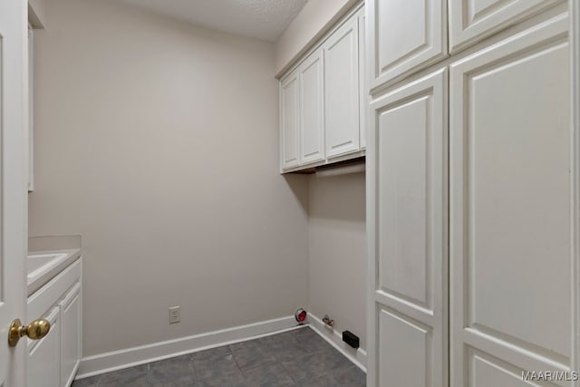 clothes washing area with cabinets and dark tile patterned floors