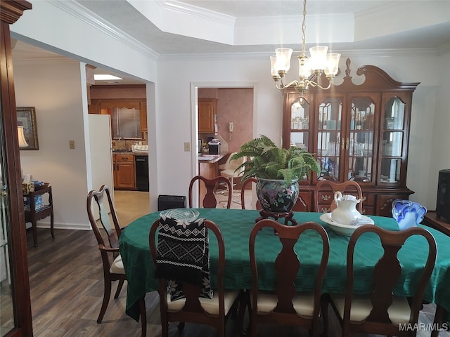 dining area with an inviting chandelier, hardwood / wood-style flooring, a raised ceiling, and ornamental molding