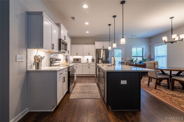 kitchen featuring hanging light fixtures, an island with sink, dark hardwood / wood-style flooring, white cabinetry, and stainless steel appliances