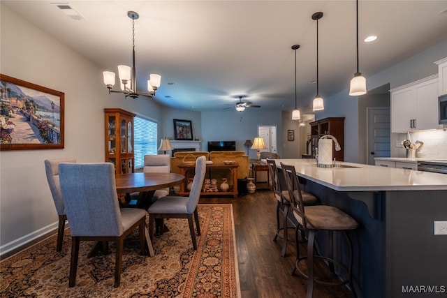 dining room with ceiling fan with notable chandelier, dark hardwood / wood-style floors, and sink