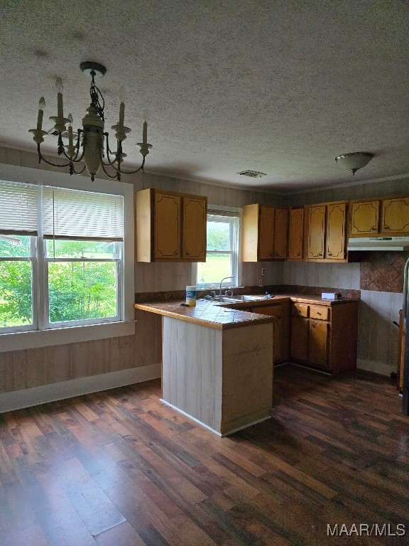 kitchen with a chandelier, dark hardwood / wood-style floors, kitchen peninsula, and tile countertops