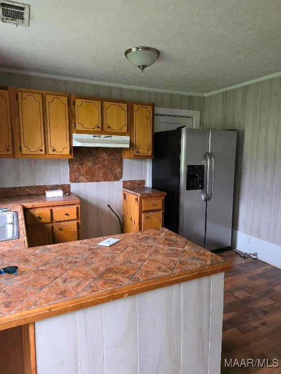 kitchen featuring stainless steel fridge with ice dispenser, tile counters, dark hardwood / wood-style floors, a textured ceiling, and kitchen peninsula