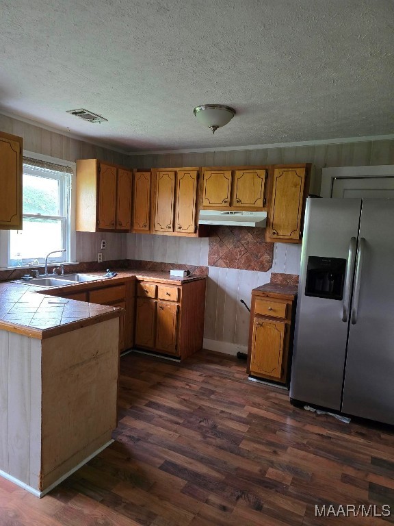 kitchen featuring stainless steel refrigerator with ice dispenser, a textured ceiling, tile counters, and dark wood-type flooring