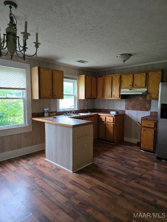 kitchen with a chandelier, sink, tile counters, dark hardwood / wood-style floors, and stainless steel fridge