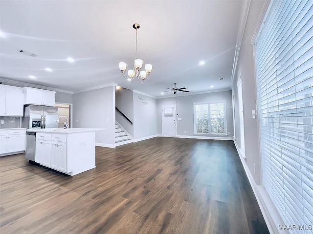 kitchen featuring crown molding, appliances with stainless steel finishes, white cabinetry, a kitchen island with sink, and decorative light fixtures