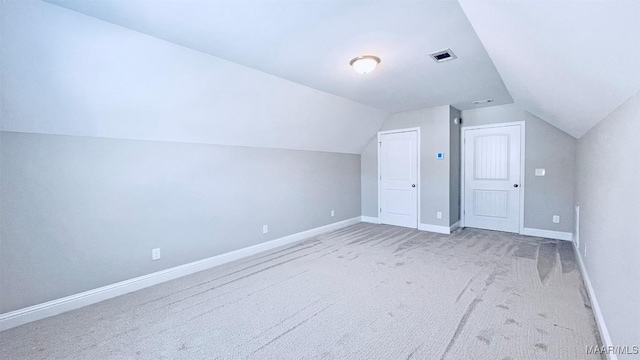 bonus room with lofted ceiling and light colored carpet