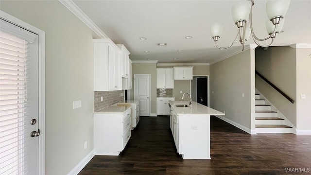 kitchen featuring sink, dark wood-type flooring, a kitchen island with sink, white cabinetry, and ornamental molding