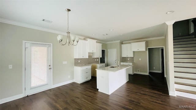 kitchen featuring white cabinetry, crown molding, dark hardwood / wood-style floors, an island with sink, and pendant lighting