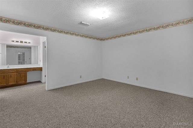 carpeted empty room featuring sink and a textured ceiling