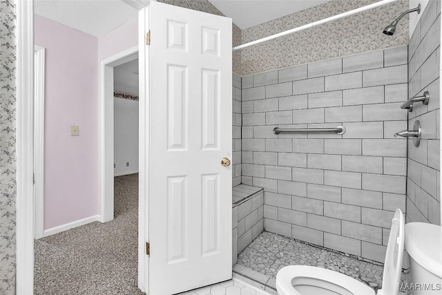 bathroom featuring a tile shower and toilet