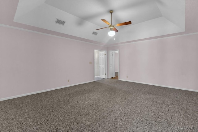 empty room with ornamental molding, a raised ceiling, ceiling fan, and carpet