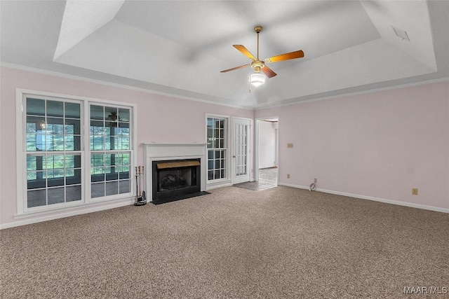 unfurnished living room with crown molding, ceiling fan, a raised ceiling, and carpet