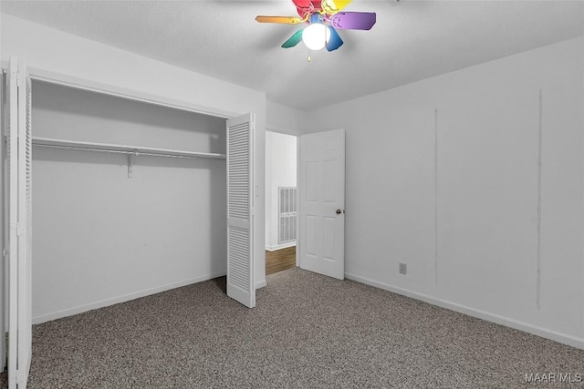 unfurnished bedroom with ceiling fan, a textured ceiling, a closet, and dark colored carpet