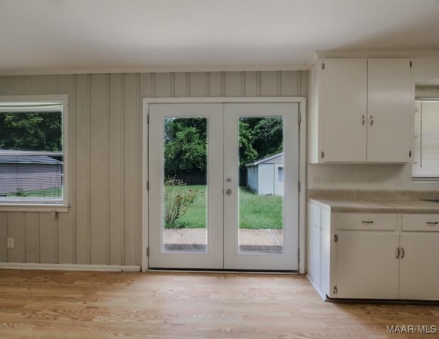 entryway featuring french doors, baseboards, and light wood finished floors