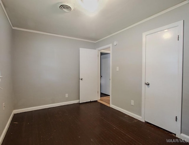 spare room featuring baseboards, visible vents, wood finished floors, and ornamental molding