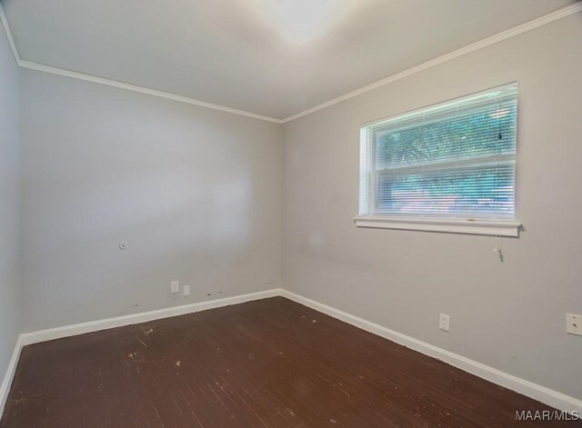 empty room featuring ornamental molding, baseboards, and wood finished floors