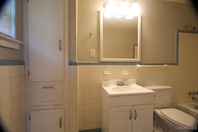 full bath with toilet, a wainscoted wall, tile walls, and vanity