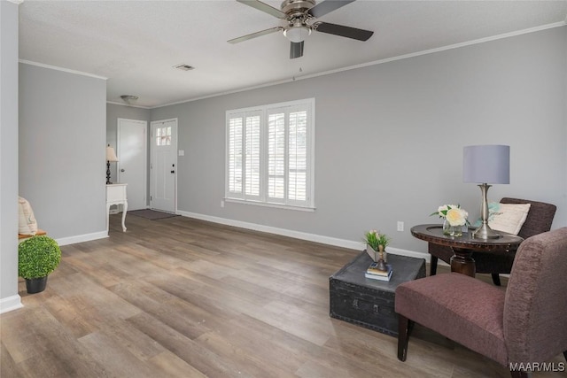 living area with ceiling fan, ornamental molding, and light wood-type flooring