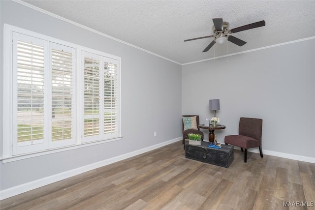 living area featuring crown molding, ceiling fan, wood-type flooring, and a textured ceiling