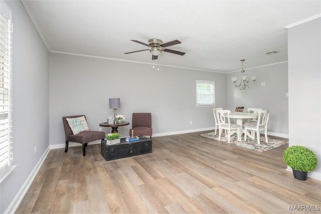 sitting room with hardwood / wood-style floors, ceiling fan with notable chandelier, and crown molding