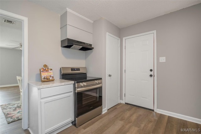 kitchen featuring white cabinets, light hardwood / wood-style flooring, stainless steel stove, and range hood