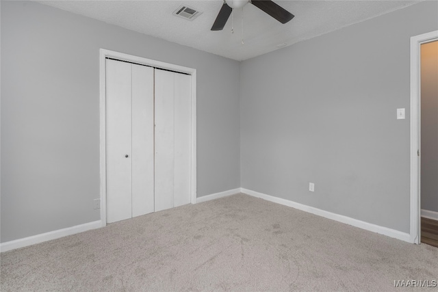 unfurnished bedroom featuring carpet flooring, a textured ceiling, a closet, and ceiling fan