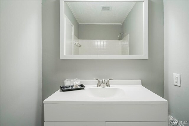 bathroom featuring vanity, ornamental molding, and a textured ceiling