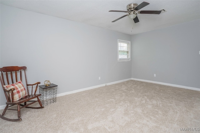 living area with light carpet, ceiling fan, and a textured ceiling